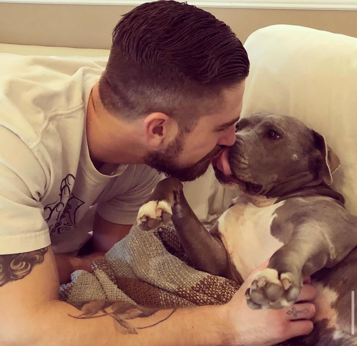 Steve giving a dog a kiss on a couch